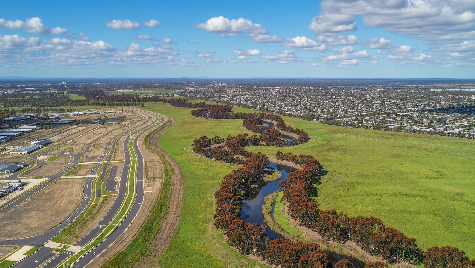 Aerial view of a new master-planned community beside a natural creek corridor at Cardinia Creek South.